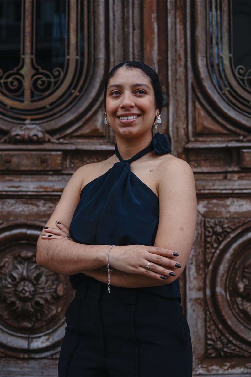 Retrato feminino diante de uma porta histórica de madeira entalhada