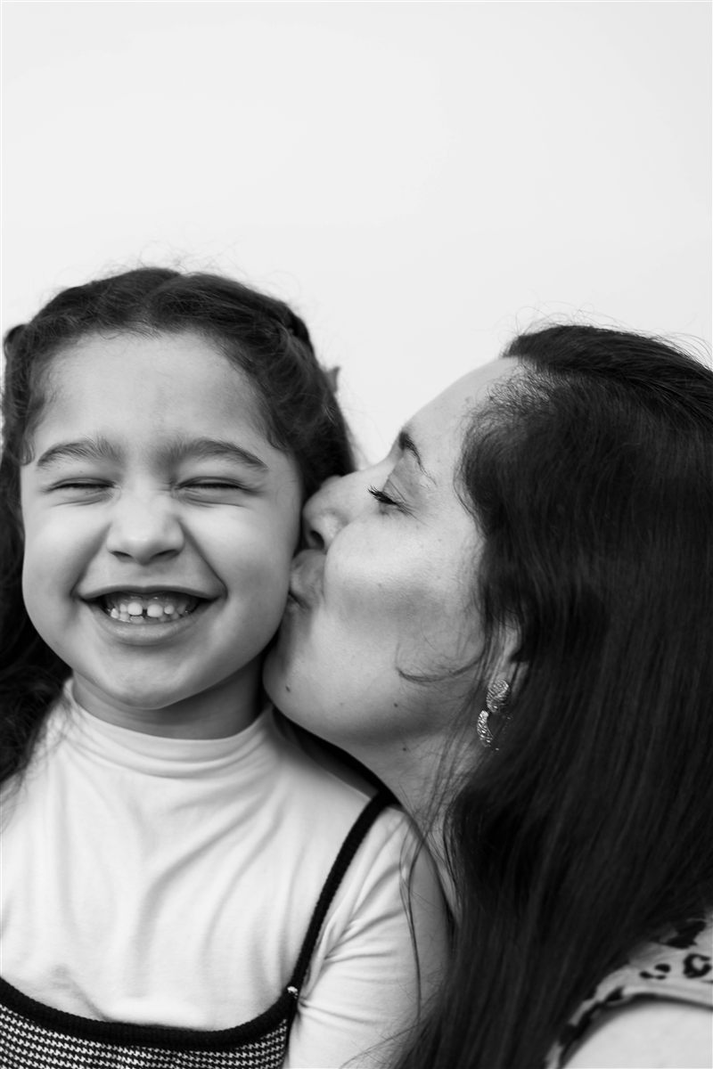 Mãe beija a filha em um retrato em preto e branco