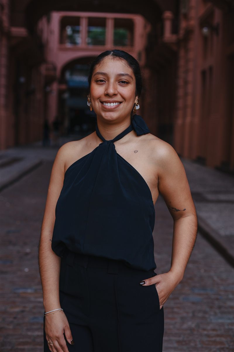 Mulher sorrindo em uma passagem de arquitetura rosada